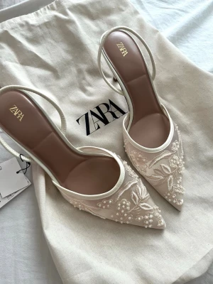Zara klackar  - Klackskor med spetsig tå och elastisk rem baktill. Skorna är slutsålda. De har broderade detaljer och pärlor. Perfekta till ett bröllop. Helt nya men SE SISTA BILDEN !