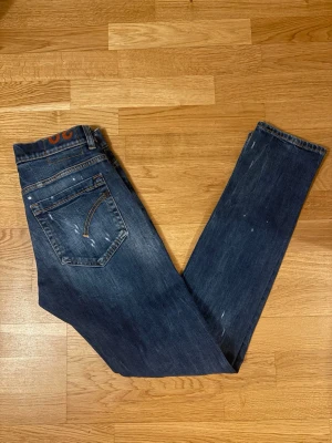 Dondup George  - Snygga mörkblå slim fit jeans från Dondup med slitna detaljer och orange sömmar. Klassisk femficksmodell. Perfekta för en avslappnad och trendig look.