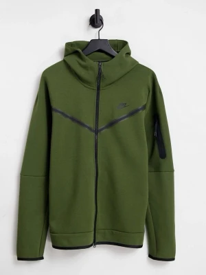 Olivgrön Nike tech Original  - Nike hoodie i olivgrönt med hel dragkedja och svart Nike-logga på bröstet. Hoodien har huva, svarta detaljer längs dragkedjan och en praktisk ficka med dragkedja på ärmen. Tillverkad i mjukt material, perfekt för en sportig och avslappnad stil.