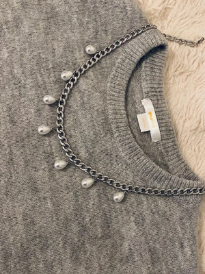 Kedjehalsband med pärldroppar - Snyggt halsband med en silverfärgad rostfritt kedja och sju hängande vita pärldroppar. Kedjan har en klassisk länkdesign och pärlorna ger en cool kontrast till metallen. Perfekt accessoar för att lyfta din outfit.