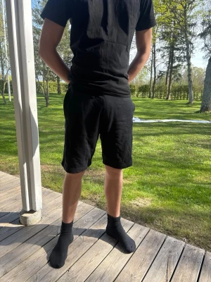 Svarta shorts  - Säljer ett par svarta shorts  med normal passform och elastisk midja. Shortsen har fickor på sidorna och ena sidan baktill, perfekta för chill dagar eller när du vill ha det bekvämt.