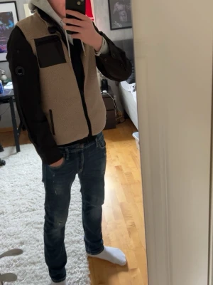 Svart overshirt från C.P. Company - Säljer en svart overshirt från C.P. Company med dragkedja framtill, bröstficka och den ikoniska linsen på ärmen. Som ni ser så är batchen tyvärr lite sliten då jag råkat skrapa emot, utöver de så är den i super fint skick.