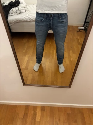 Slim Glenn blå jeans  - Snygga slim Glenn jeans ifrån Jack and Jones med klassisk design. Jeansen har smal passform och sitter bra längs benen. Perfekta för en trendig och avslappnad stil. Ord pris 999kr. Obs har två små slitningar på båda fickorna bak på jeansen som är laggade. Samt ett hål (näst sista bilden) men syns knappt vid användning.