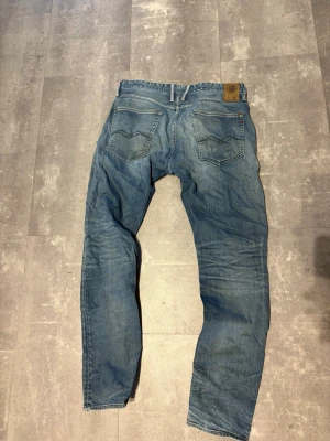 Replay Jeans  - Säljer ett par klassiska blå jeans från replay Jeans med raka ben och fem fickor. Jeansen har ljus tvätt, kontrastsömmar och läderpatch bak i midjan. Tillverkade i bomull och har en avslappnad passform. Perfekta till vardagslooken!