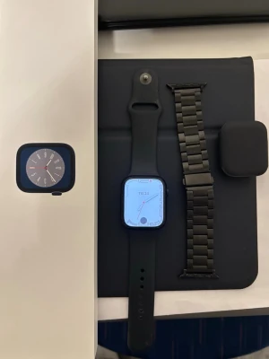 Apple Watch Series 8 Midnight 45mm - Apple Watch Series 8 med midnight aluminiumboett och svart sportband. Klockan har en fyrkantig form och kommer med extra svart metallarmband. Modern design och stor, tydlig skärm. Perfekt för dig som vill ha koll på både träning och notiser direkt på handleden.