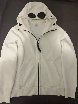Vit hoodie från C.P. Company - Säljer min vita hoddie från C.P Company för den är för liten. Storlek M. Väldigt bra skick för använde den typ aldrig. Nypris 3500kr. Säljer för jättebra pris, 449kr