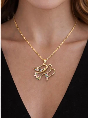 Guldhalsband med duvberlock och stenar - Snyggt halsband i guldfärgad metall med en duvformad berlock dekorerad med små färgglada stenar. Kedjan är tunn och elegant, perfekt för att ge din outfit en unik touch. Berlocken har en modern design med glittrande detaljer. Halsbandet är  i rostfritt /nickelfritt material med högkvalite