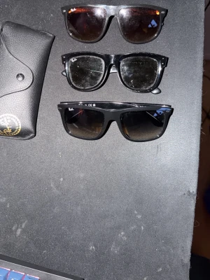 3 par Svarta Ray-Ban solglasögon - Ray-Ban solglasögon med klassisk svart båge och mörka glas. Modellen har en rektangulär form och kommer med original Ray-Ban fodral i svart skinn. Perfekt för dig som vill ha en tidlös och ikonisk look. Rayban boyfriend 2-2100kr rayban boyfriend 1 1700kr rayban wayfarer 2100kr