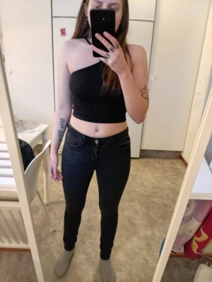 Svarta skinny jeans med låg midja - Säljer ett par svarta skinny jeans med låg midja och klassisk femficksdesign. Jeansen har en tight passform och är tillverkade i stretchigt material som sitter snyggt och bekvämt. Perfekta för dig som gillar en stilren och modern look.