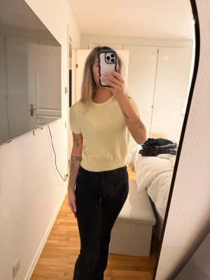 Ljusgul stickad kortärmad tröja - Säljer en ljusgul stickad tröja med korta ärmar och rund hals. Tröjan har ribbstickad nederkant och är i mjukt material, perfekt för att skapa en chill och stilren look. Passar dig som gillar enkel och clean design.