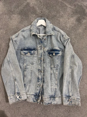 Ljusblå oversized jeansjacka - Säljer en klassisk ljusblå jeansjacka med två bröstfickor med lock och knapp, samt knappar vid ärmslut och framtill. Jackan har markerade sömmar och slitna detaljer vid fickor och nederkant för en cool vintagekänsla. Är från Veromoda i storlek S💗 knappt använd och ser helt ny ut.