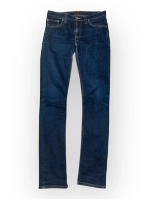 Mörkblå jeans från Nudie Jeans - Dessa Nudie Jeans har en klassisk blå färg och en slim fit-passform. De är i mycket gott skick med minimala tecken på användning.  Midja: 38 cm Innerbenslängd: 81 cm Benslut: 16 cm Framre gren: 22 cm Total längd: 106 cm  ⭐️ Skick: 8/10 🎲 Storlek: 28/34 🎨 Färg: Blå 📦 Snabb och omsorgsfull frakt.