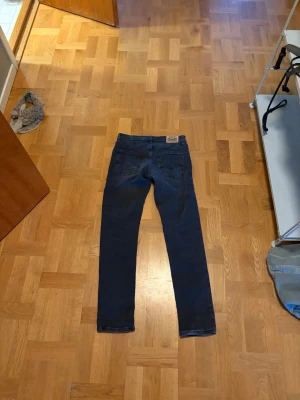Mörkblå Levi's jeans slim fit - Säljer ett par mörkblå slim fit jeans från Levi's med klassiska femficksdetaljer och läderpatch bak i midjan. Jeansen har raka ben och är tillverkade i denim med en snygg tvätt. Perfekta för dig som gillar en tidlös och clean look.