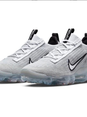 Nike Air Vapormax vita sneakers - Nike Air Vapormax sneakers i vitt med stickad ovandel och svart Swoosh-logga på sidan. Skorna har genomskinlig sula med synliga luftbubblor och vita skosnören. Modern och sportig design med detaljer i svart på plösen och hälen. HELT NYA