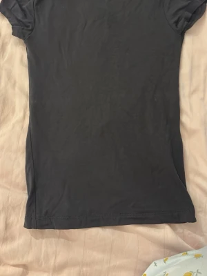 Svart tight topp med öppen rygg - En svart, tight topp med korta ärmar och en djup öppen rygg. Knappt använd. 