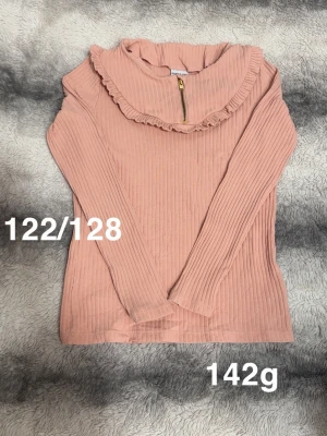 Rosa ribbad tröja med volangkrage - Supersöt rosa långärmad tröja med ribbad struktur och volangkrage. Dragkedja framtill vid halsen ger en extra detalj. Perfekt för dig som gillar en gullig och trendig stil.🌸 Fint använt skick. Storlek 122/128