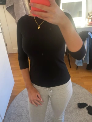 Svart topp från Vero Moda - En enkel och stilren svart topp från Vero Moda med trekvartsärm och rund hals. Toppen har en tight passform och är tillverkad i mjukt material som sitter skönt mot kroppen. Perfekt att matcha med både jeans och kjol.