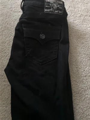 Svarta jeans från True Religion - Säljer ett par svarta jeans från True Religion jeans mid raise, endast testade och tyvärr spillt lite lim inte så synligt säljer dom därav storleken inte passade mig. Pris kan diskuteras!!