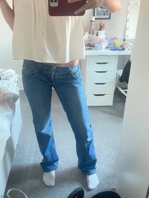 Blå bootcut jeans med låg midja - Säljer ett par blå bootcut jeans med låg midja och snygga slitningar. Jeansen är helt nya och aldrig andvända, köpt för 800 men kan gå ner i pris!
