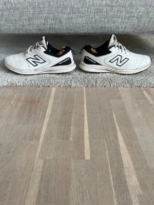 Vita New Balance sneakers med svart detalj - Snygga vita sneakers från New Balance med svarta detaljer och klassisk N-logga på sidorna. Skorna har lågt skaft och är tillverkade i syntetmaterial och textil. Perfekta för en sportig och stilren look. Ord pris: 999kr mitt pris: 399
