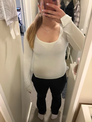 Vit långärmad topp från gina - Säljer en vit långärmad topp med rundad urringning och slits längst ut i ärmarna. Toppen är tight i passformen och har en enkel, stilren design som passar till mycket. Perfekt basplagg för din garderob.