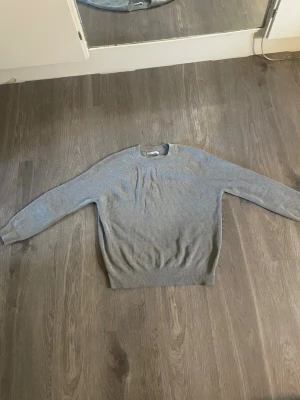 Ljusgrå stickad tröja från ZARA - Snygg ljusgrå stickad tröja från ZARA med rund halsringning och ribbade muddar. Perfekt för lager-på-lager och enkel att matcha med olika outfits. Tröjan har en klassisk passform och är tillverkad i mjukt material.