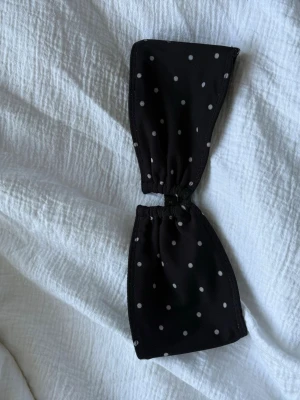 Svart prickig bandeau bikiniöverdel - Säljer en sjukt snygg svart bandeau bikiniöverdel med vita prickar. Aldrig använd då den är för liten. 