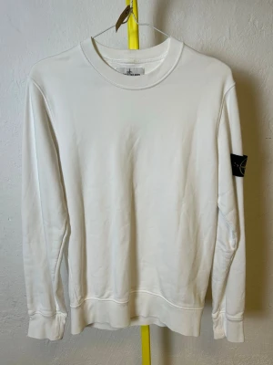 Vit collegetröja från Stone Island  - Denna vara kommer att auktioneras ut på Plick Live den 27 maj klockan 18:00