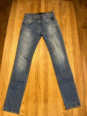 Blå stretch replay jeans  - Snygga blå slim fit jeans från replay med klassisk femficksdesign och diskreta slitningar framtill. Jeansen har normal midja, raka ben och är tillverkade i mjuk denim med lite stretch för extra komfort. Perfekta till en avslappnad stil.