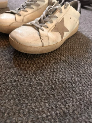  Golden Goose  - Snygga vita sneakers från Golden Goose med en grå stjärna på sidan och svart häl. Bra skick ändå. Typ 7/10