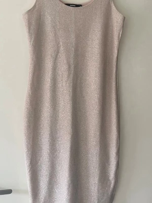 Glittrig ljusrosa klänning BIK BOK - Säljer en glittrig ljusrosa klänning från BIK BOK. Klänningen är ärmlös med rund halsringning och har en rak, kroppsnära passform. Materialet skimrar snyggt i ljuset och ger en festlig känsla. Perfekt för dig som vill sticka ut med stil.