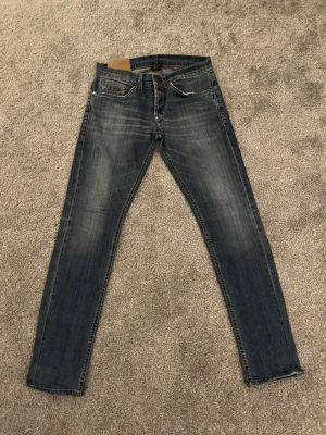 Dondup George W32 - Snygga blå skinny fit jeans med lätt slitna detaljer. Jeansen har normal midja och raka ben, perfekta för en avslappnad och trendig look. Materialet är troligtvis bomull med lite stretch för extra komfort. Hör av dig vid minsta lilla fundering, eller prisförslag.