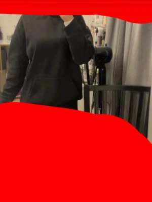 Svart hoodie med grafiskt tryck - Säljer en svart hoodie med huva och magficka. På ryggen finns ett stort grafiskt tryck i rosa och vitt med texten 'INTENSE FEELINGS' och en staty-inspirerad illustration. Perfekt för dig som gillar streetwear och vill sticka ut lite extra.