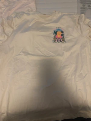 Vit Casa Blanca t-shirt med tryck - Säljer en vit t-shirt från Casa Blanca med färgglatt grafiskt tryck på bröstet och ryggen. Helt ny