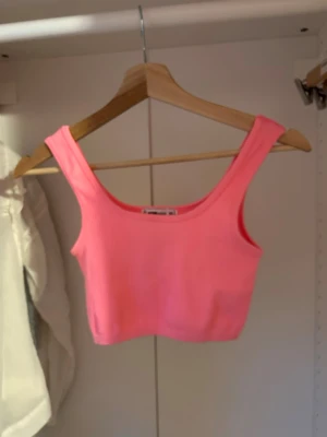 Rosa ribbad linnetopp FB Sister - Snygg rosa ribbad linnetopp från FB Sister i storlek XS. Toppen är croppad och har breda axelband samt rundad halsringning. Perfekt att styla med höga jeans eller kjol för en trendig look. Har även i två andra färger 