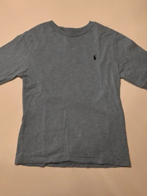 Blå långärmad t-shirt från Ralph Lauren - Klassisk ljusblå t-shirt från Ralph Lauren med rund halsringning. Tillverkad i mjuk bomull för en skön och avslappnad passform. Perfekt basplagg till garderoben.