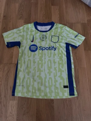 FC Barcelona Dri-Fit ADV matchtröja - Snygg FC Barcelona matchtröja från Nike med Dri-Fit ADV-teknologi. Tröjan är ljusgul med limegröna mönster, blå detaljer och tryckta loggor. Spotify-logga på bröstet och officiella klubbmärken. Perfekt för fotbollsträning eller att bära till vardags.