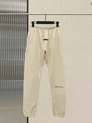 Beige Essentials mjukisbyxor - Säljer ett par snygga beige mjukisbyxor från Essentials med diskret logga på benet. Byxorna har resår i midjan och vid bensluten samt sidofickor. Perfekta för en chill och avslappnad stil. Tillverkade i mjukt material för maximal komfort.