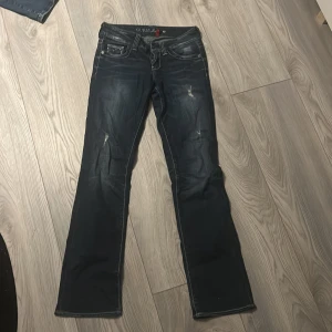 Low waist bootcut jeans från Guess - Snygga blå jeans från Guess med bootcut passform och slitna detaljer. Vet ej exakt storlek men skulle säga XS/34. Säjer då de är för små 💕
