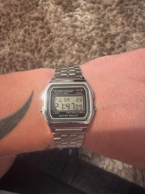 Digital silverklocka retro stil - Klassisk digital klocka i retrostil från WR med silverfärgat armband i metall. Klockan har rektangulär display med tid, datum och alarmfunktion. Länkat armband och tydlig digital skärm ger en tidlös look.