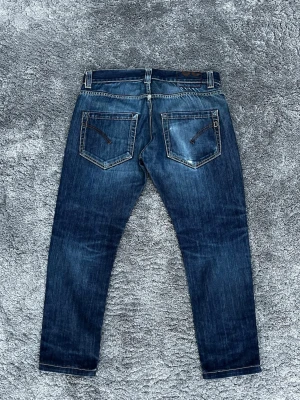 Mörkblå slim jeans från Dondup - Snygga mörkblå jeans från Dondup med raka ben och klassisk femficksdesign. Jeansen har kontrastsömmar och slitningar för en cool look. Materialet är denim och passformen är normal. Perfekta för en avslappnad stil. W32/W31 L28