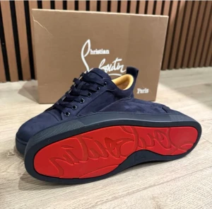 Mörkblå sneakers från Christian Louboutin - Snygga mörkblå sneakers från Christian Louboutin med ikonisk röd sula och guldfärgad logga på innersulan. Skorna har en klassisk låg siluett, ovandel i mocka och matchande mörkblå snörning. Perfekta för dig som vill sticka ut med exklusiv stil. Storlek 44, 9/10 skick . Dm för frågor 