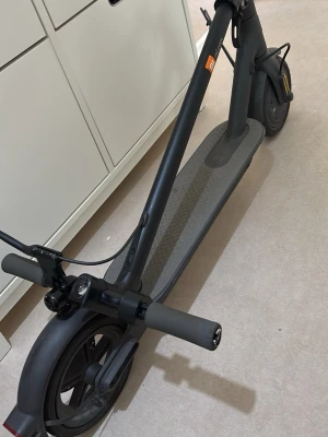 Svart elscooter från Xiaomi - Säljer en svart elscooter från Xiaomi med digital display, ringklocka och bred fotplatta med halkskydd. Scootern har stora hjul, handbroms och gasreglage på styret. Perfekt för smidig transport i stan eller till skolan.