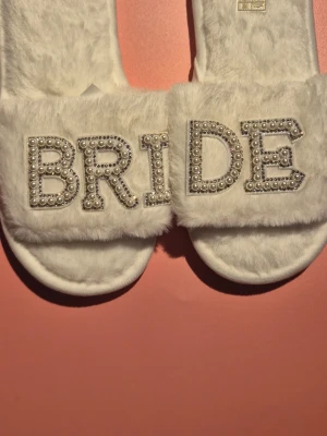 White Fuzzy BRIDE Slippers – Size 36–37 – New - New white fuzzy BRIDE slippers with pearl & rhinestone detail. Size 36–37. Soft, comfy, and perfect for wedding morning, bridal shower, or honeymoon. Ships same day in most cases.