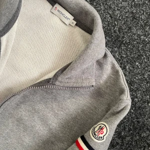 Moncler fullzip  - Säljer en grå Moncler fullzip i fint skick. Tröjan är i storlek S, men sitter mer som mindre S/XS. Självklart äkta, bara att höra av sig vid minsta lilla fundering 🫡