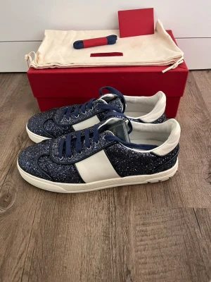 Nyskick! Valentino Flycrew Mörkblå Glitter  - Säljer nu ett par riktigt sällsynta och eftertraktade Valentino Flycrew i mörkblått glitter! ✨ Storlek 40 - mycket gott skick. ❗️Endast använda en gång!❗️Allt og medföljer (Box, dustbag, extra snören, visit kort)✅    Skorna är Självklart 100% autentiska och äkta! 🚚Alltid frakt inom 24h📦