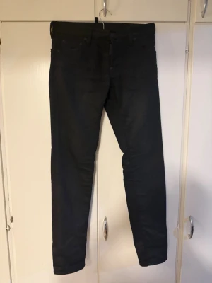 Svarta slim fit jeans - Säljer ett par svarta slim fit jeans med klassisk femficksdesign och raka ben. Jeansen har en stilren look och är perfekta för dig som gillar en enkel men snygg stil. Materialet känns mjukt och stretchigt för extra komfort.