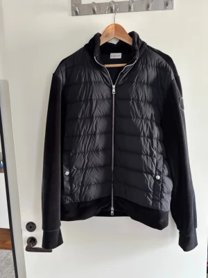 Moncler cardigan - Snygg cardigan från Moncler med quiltad framsida och släta ärmar och rygg. Jackan har dragkedja framtill, två fickor med tryckknappar och hög krage. Perfekt för kalla dagar och har en modern, sportig look. Har kvitto köpte från NK. Bara att skrev om ni har några frågor 