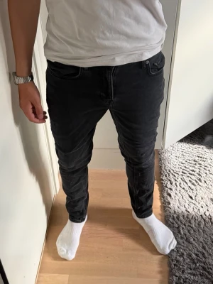 Svarta slim fit jeans herr från NN07 - Säljer ett par svarta slim fit jeans med klassisk femficksmodell och normal midja. Jeansen har smal passform hela vägen ner och är tillverkade i ett stretchigt material för extra komfort. Perfekta för dig som gillar en modern och stilren look.