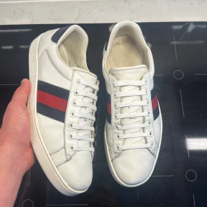 Gucci Ace skor  - Hej! Säljer nu dessa fina skorna från Gucci. Skorna är i mycket fint skick och storlek 9, vilket motsvarar ungefär 43. Fråga om innermått vid osäkerhet. Originalkort ingår. Hör av dig vid funderingar!